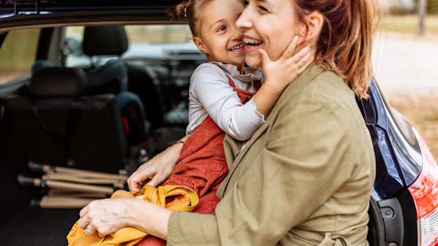 Una madre e sua figlia svuotano il bagagliaio di un’auto.