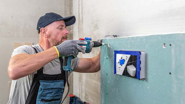 Sanitär bohrt ein Loch in die Wand