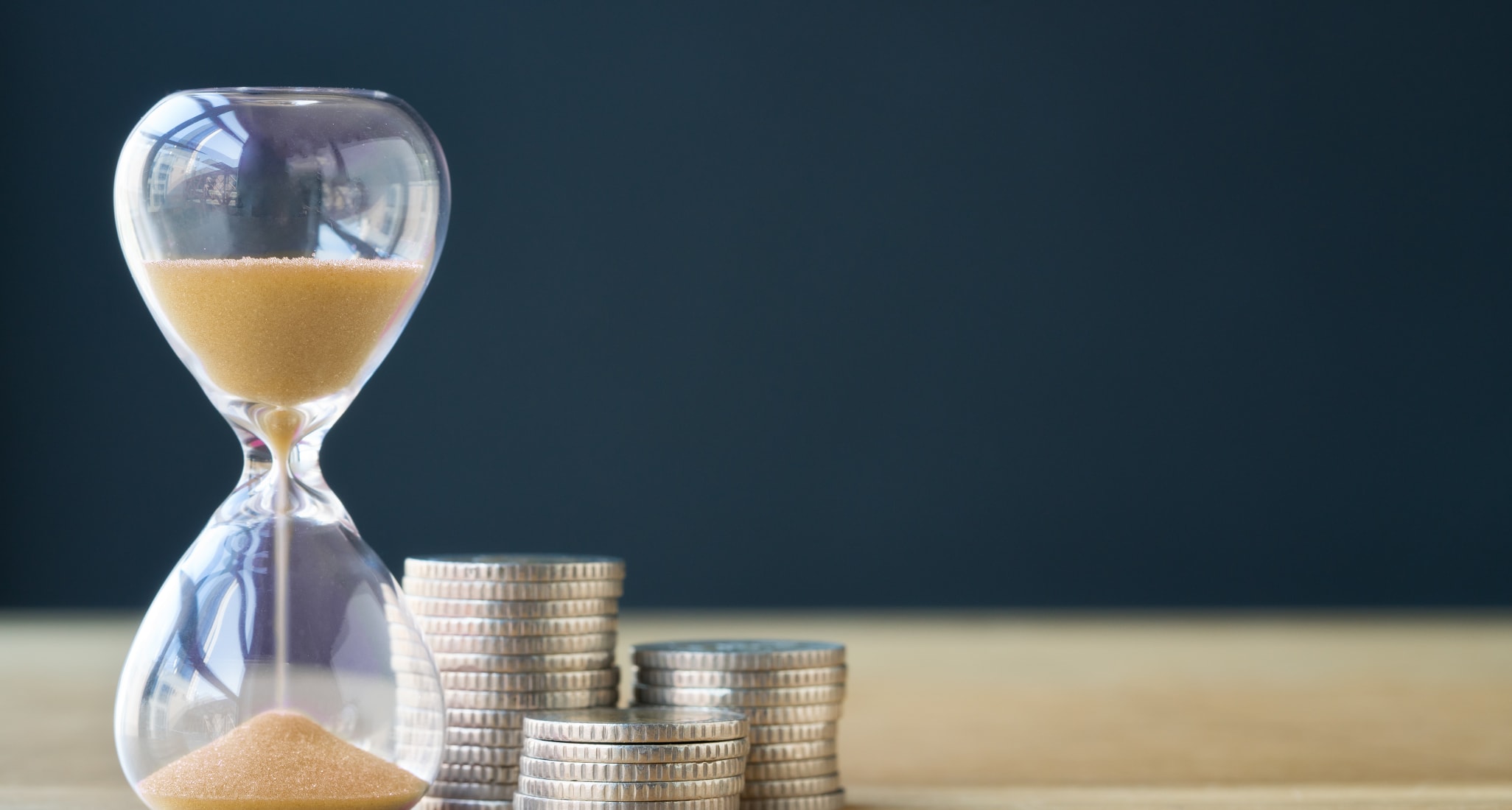 An hourglass standing next to coins.