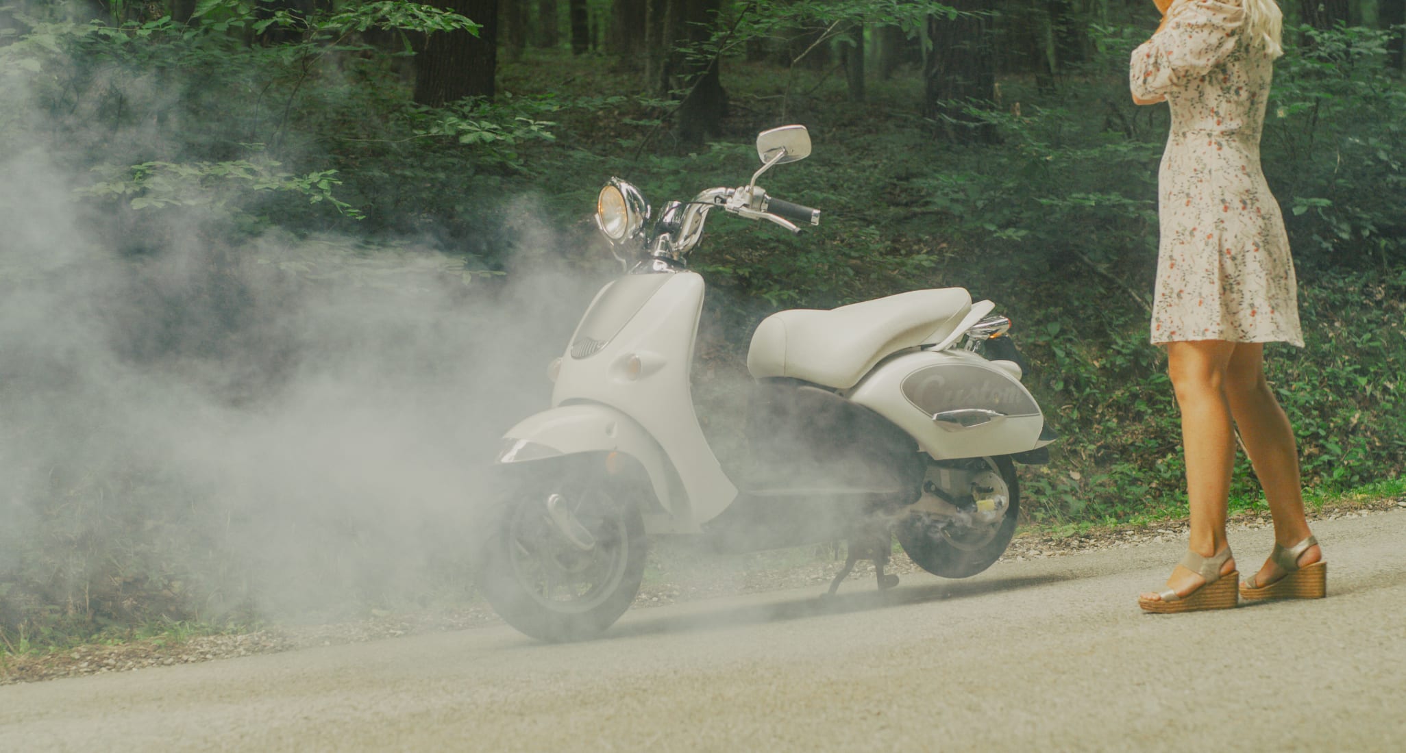 Eine Frau steht vor einem rauchenden Motorrad.