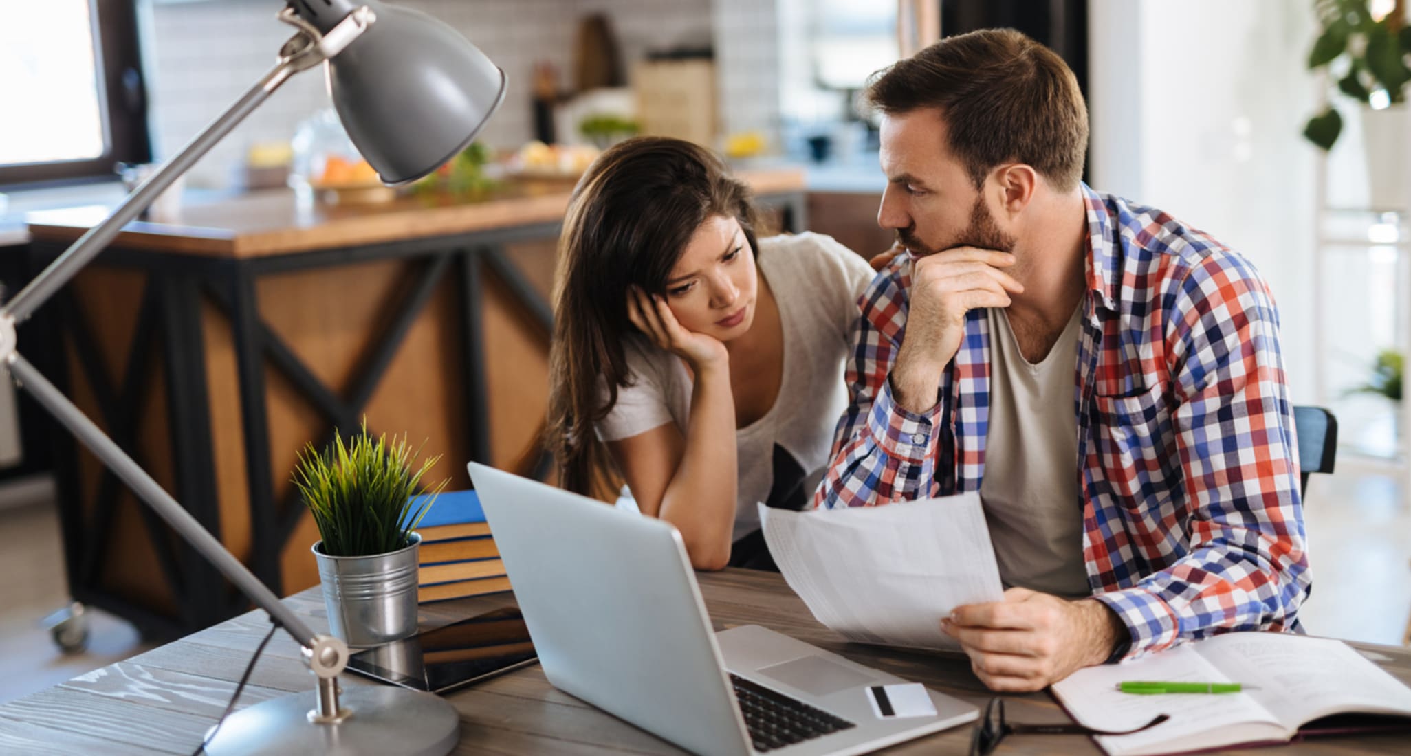 Derrière un ordinateur, un jeune couple discute du taux d’endettement et du ratio de financement externe. 