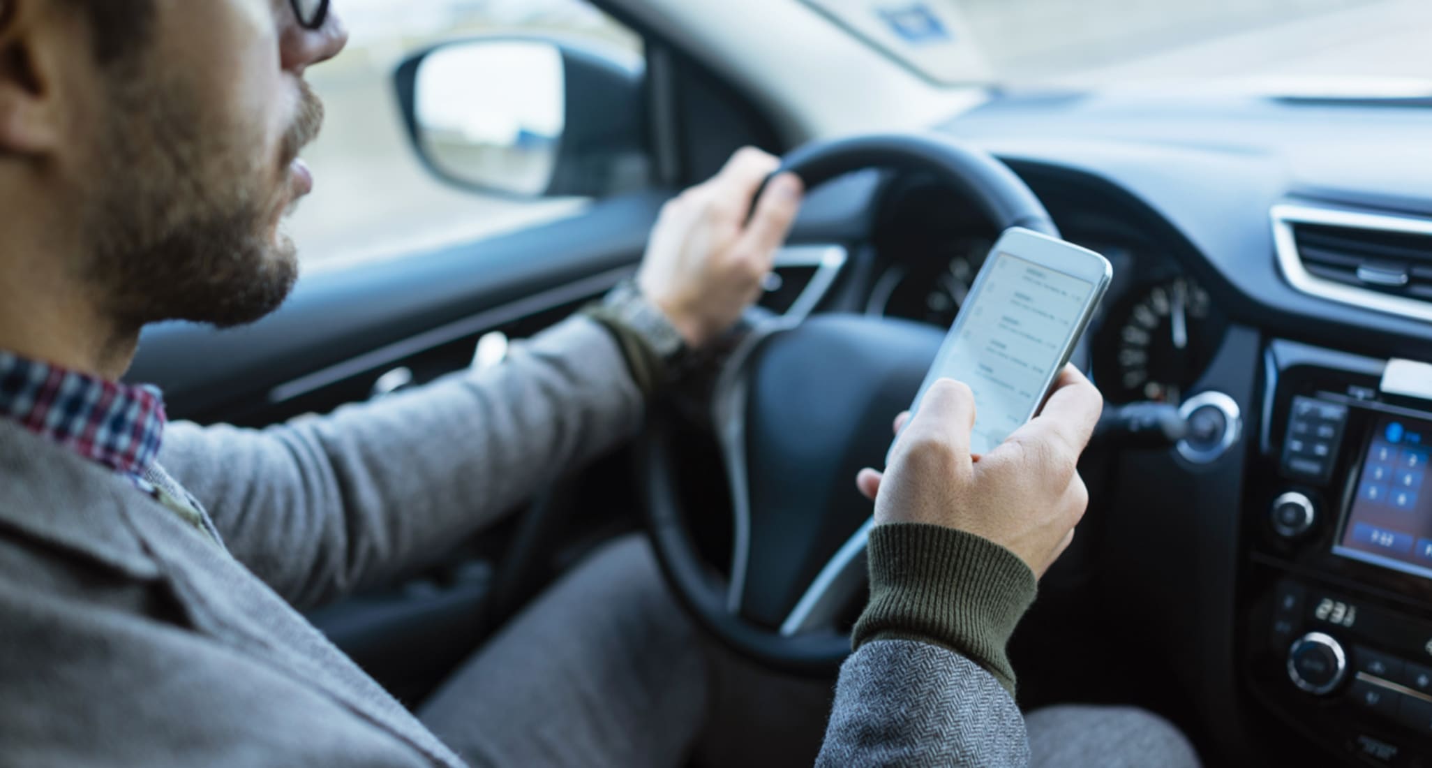 Un homme pilote une moto tout en rédigeant un message sur son téléphone.