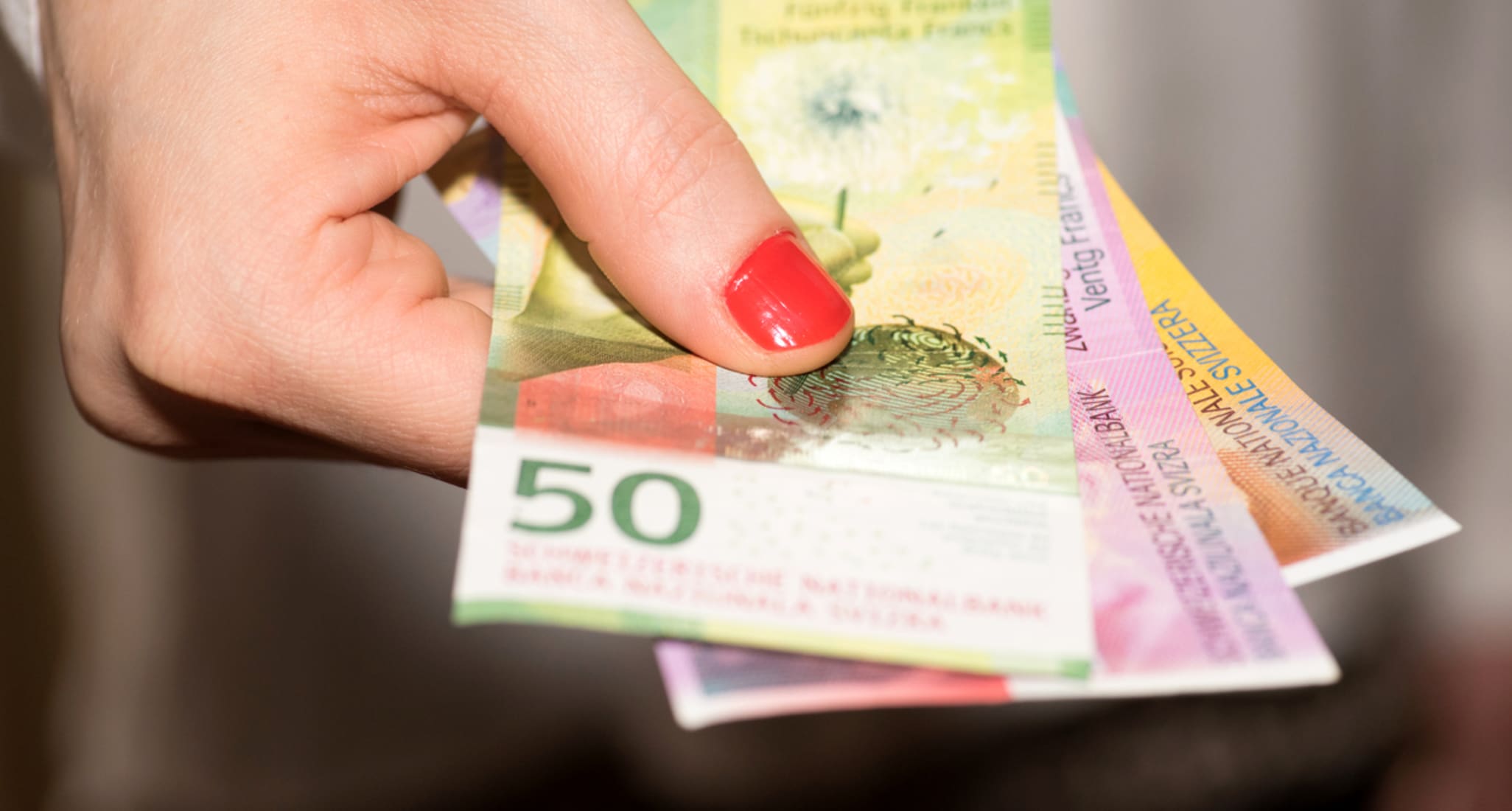 Une femme tient des billets de banque suisses.