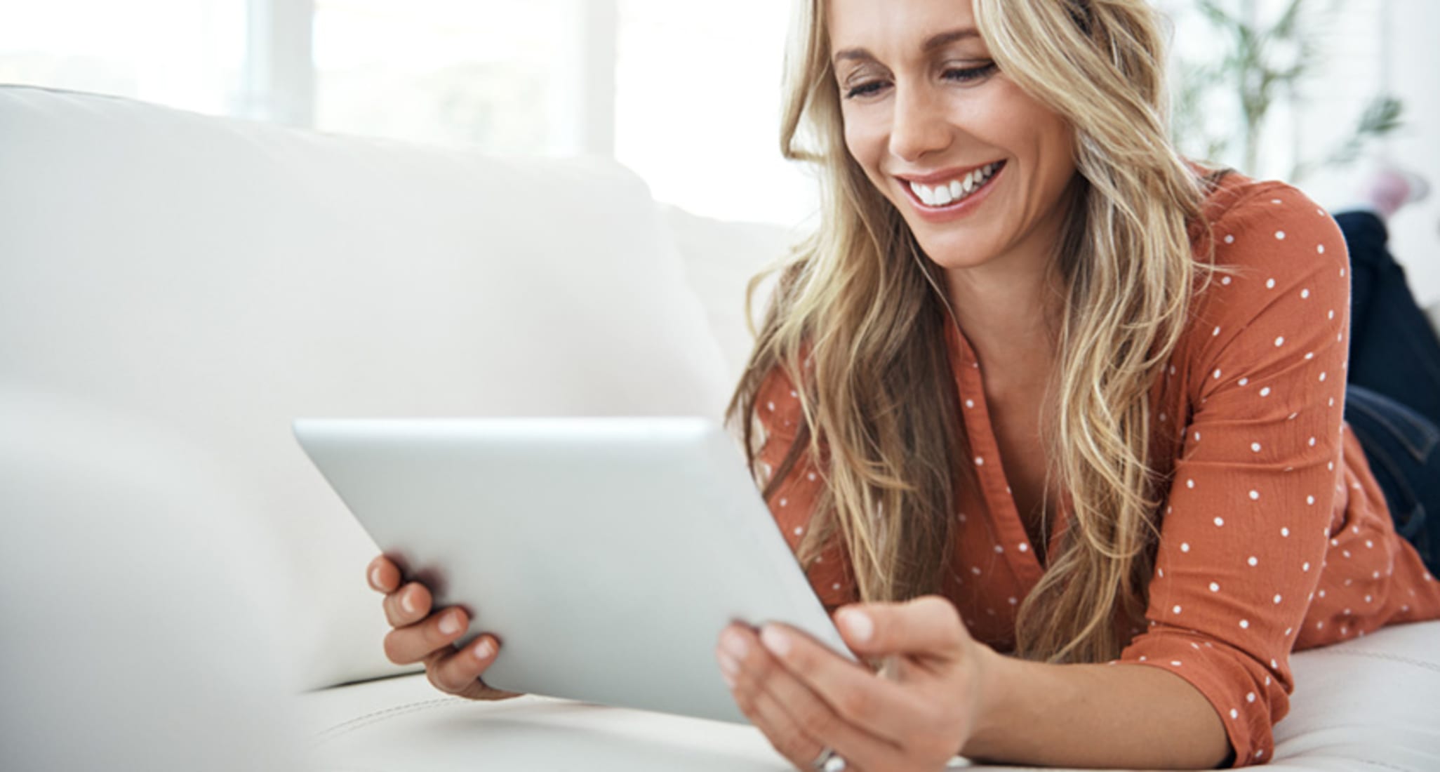 Une femme regarde une tablette en riant.