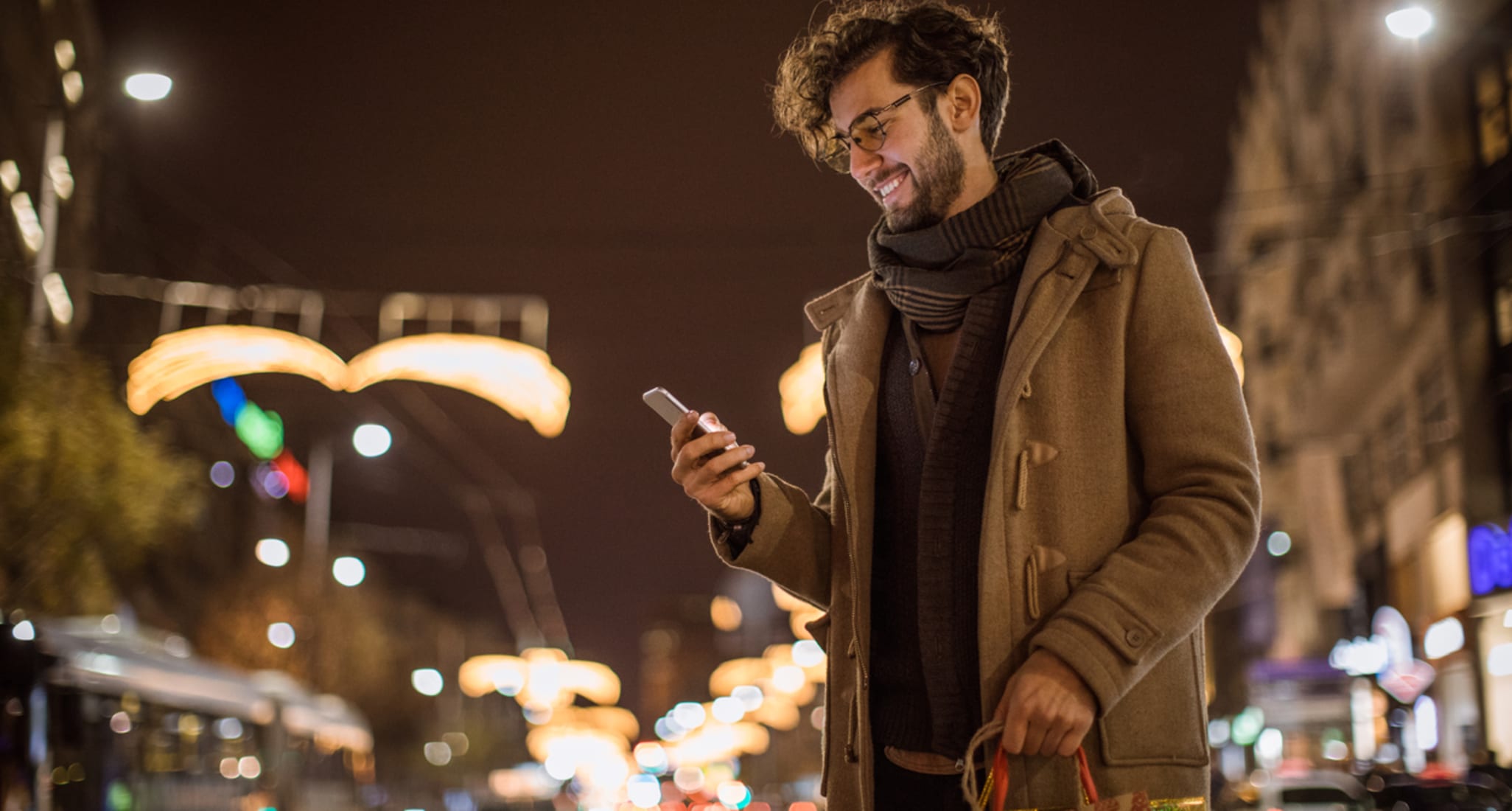 A man stands on the street. He is paying into his pillar 3a via smartphone.