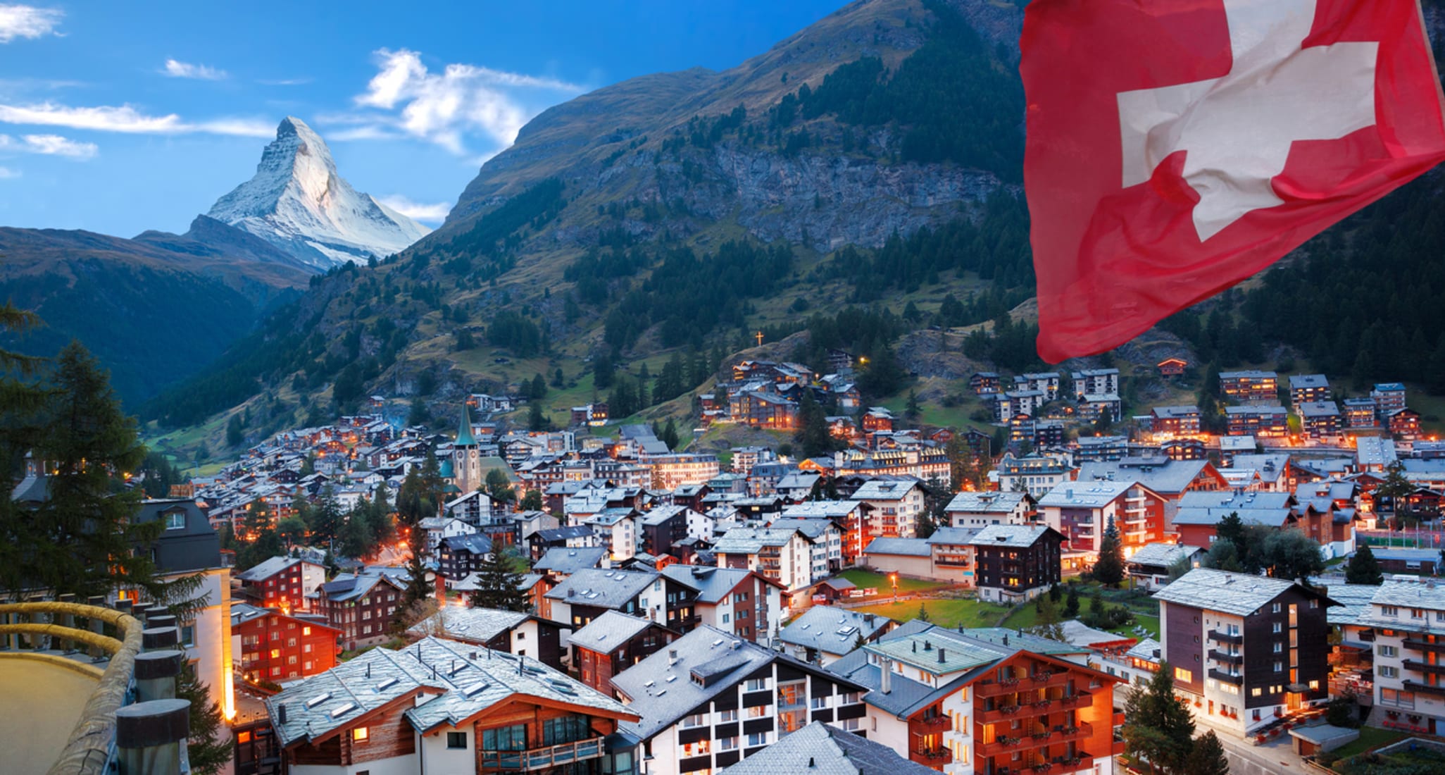 Eine Schweizer Flagge, die im Wind weht. Im Hintergrund ist das Matterhorn im Kanton Wallis zu sehen.