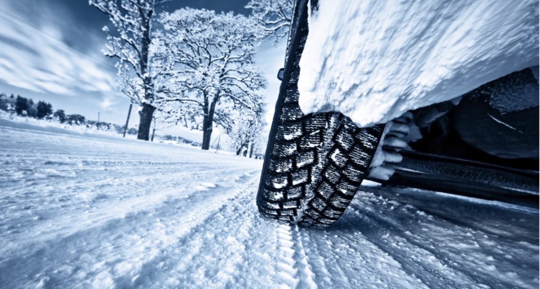 Car tyre in a winter landscape. The car leaves tyre tracks on the snow-covered road.