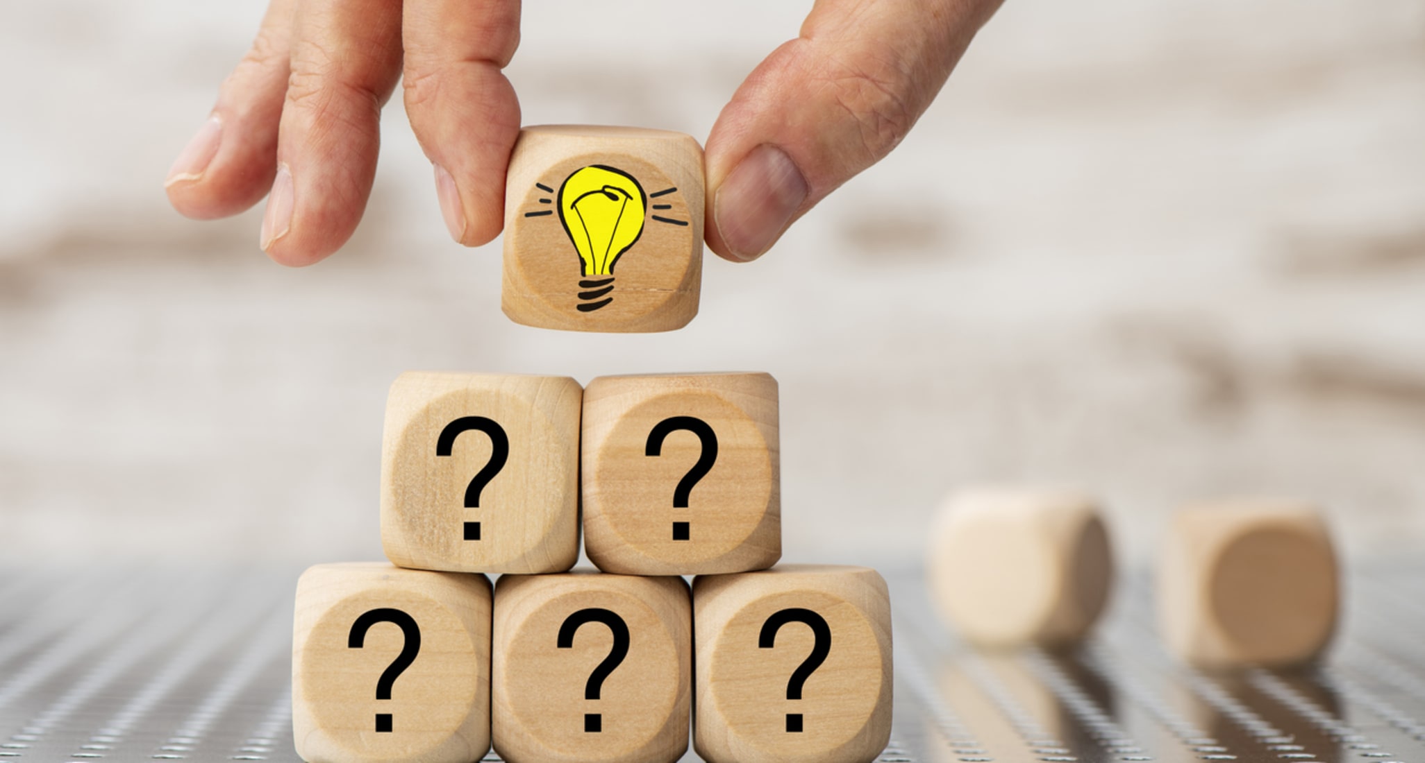 Wooden cubes arranged in a pyramid have question marks drawn on them.