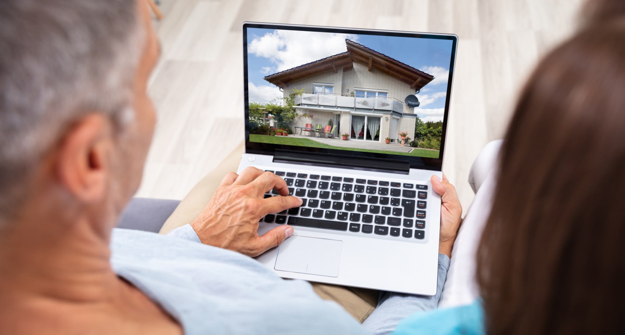 Sur un ordinateur portable, un couple marié recherche un bien immobilier