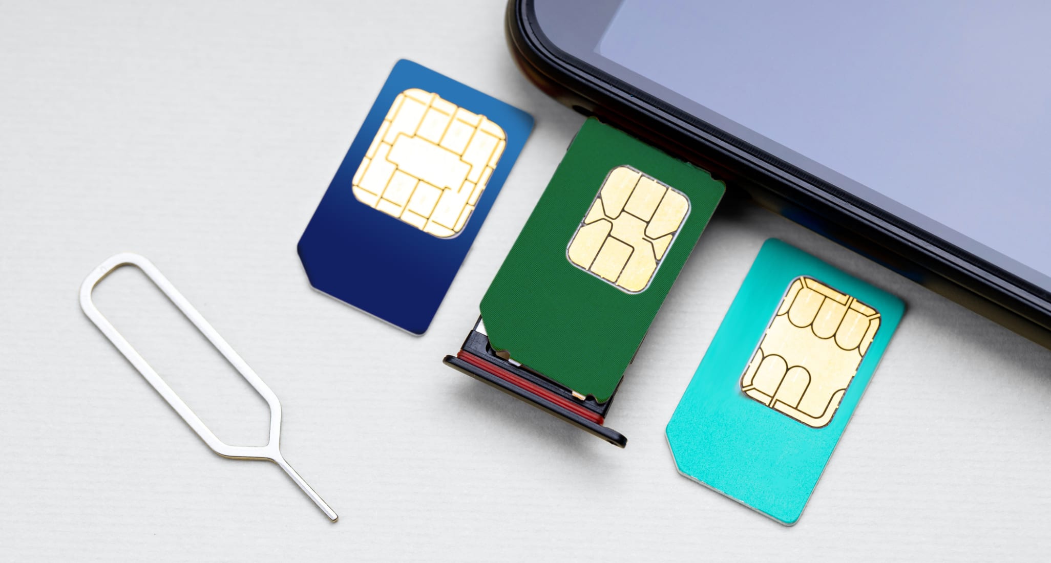 Trois cartes SIM de couleurs différentes à côté d’un smartphone.