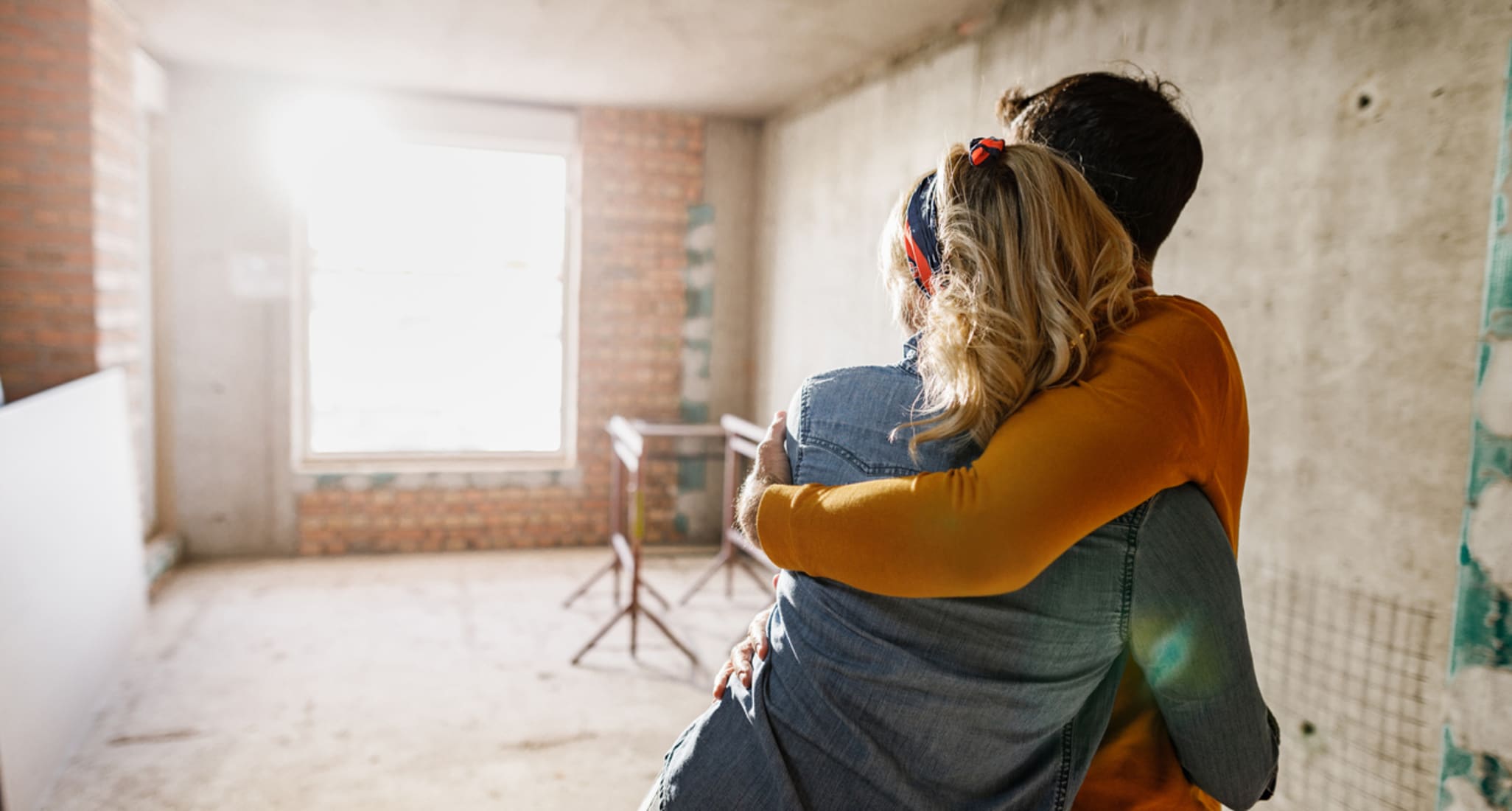 A couple in a newly built house with their arms round each other. 