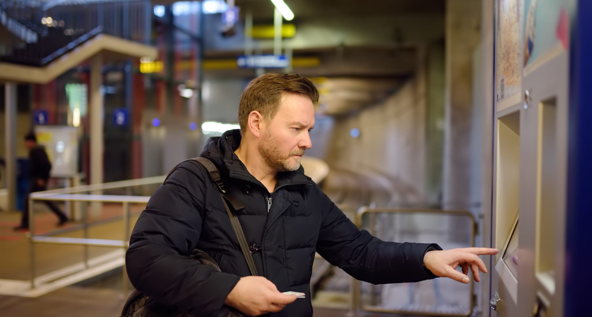 A man buying a ticket for the subway or train via a ticket machine at the station 