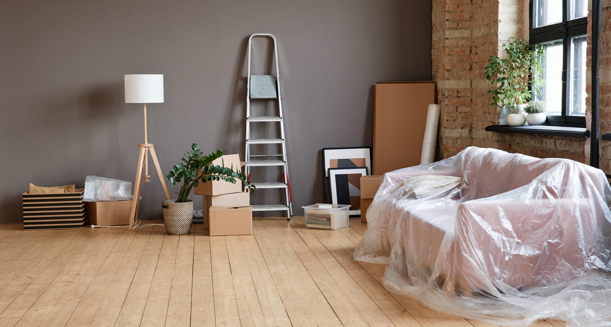 Empty spacious loft living room in modern apartment with boxes, ladder, sofa and various things