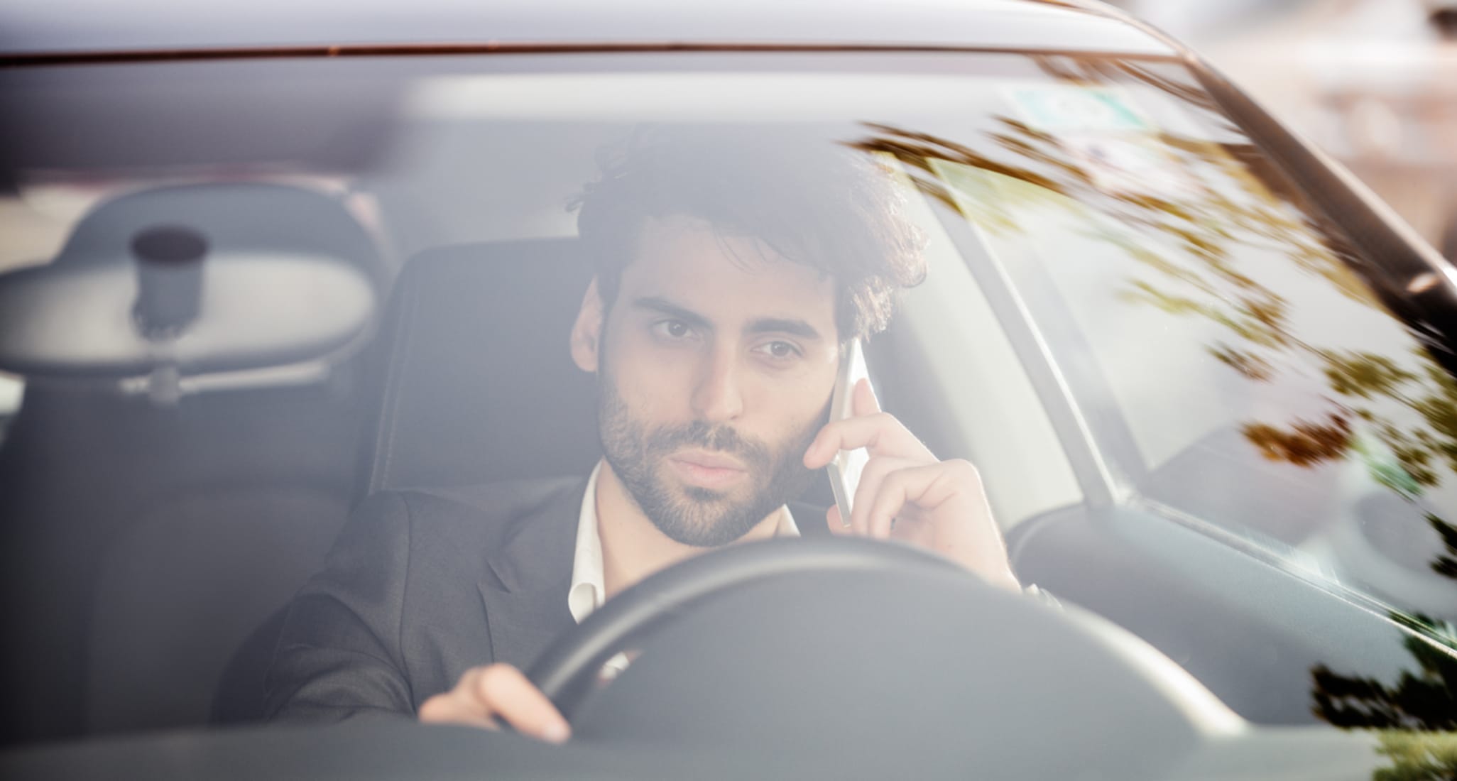 Risky driving: young man talking on the phone at the wheel