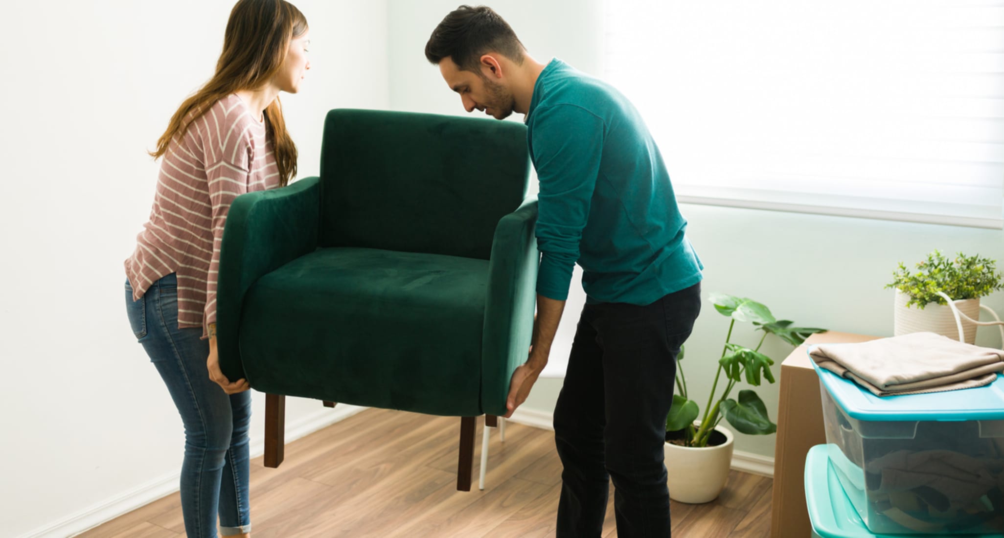 Una donna e un uomo decorano il soggiorno e dispongono i mobili.