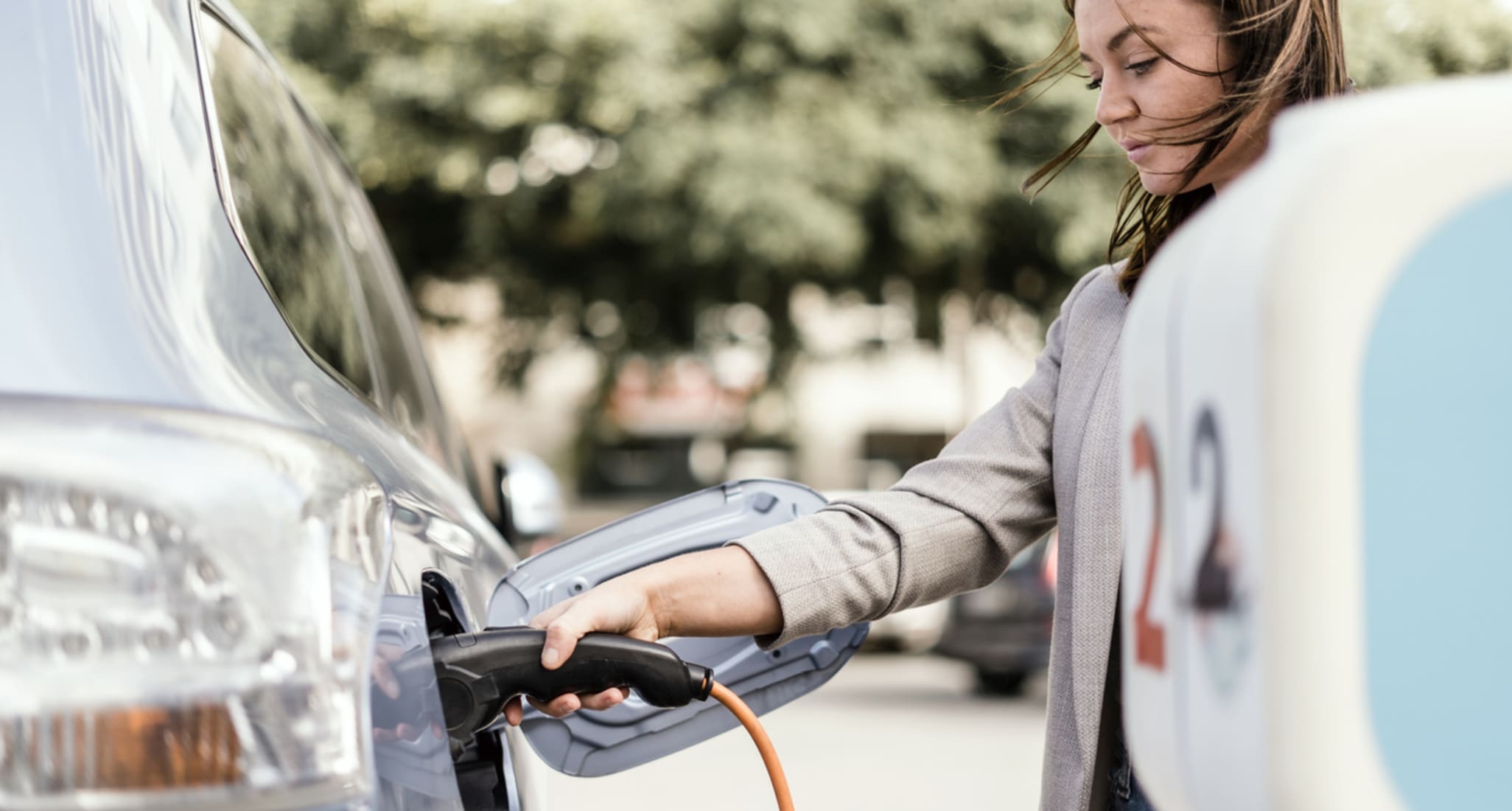 Une jeune femme recharge sa voiture électrique en ville.