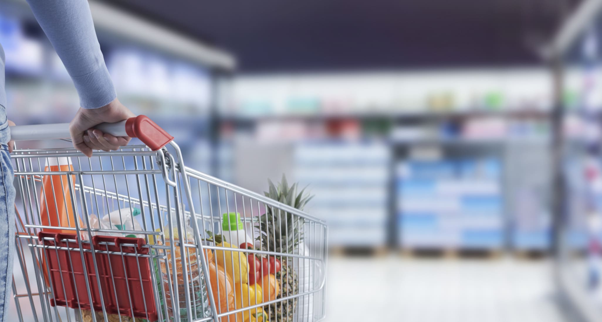 Une femme avec un chariot de courses au supermarché.