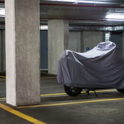 Moto recouverte d’une bâche dans un parking souterrain.