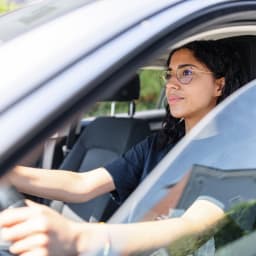 Junge Frau sitzt am Lenkrad eines Autos.