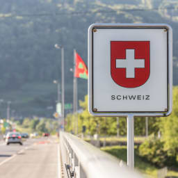 Ein Schild mit Schweizer Wappen an der Grenze zur Schweiz.