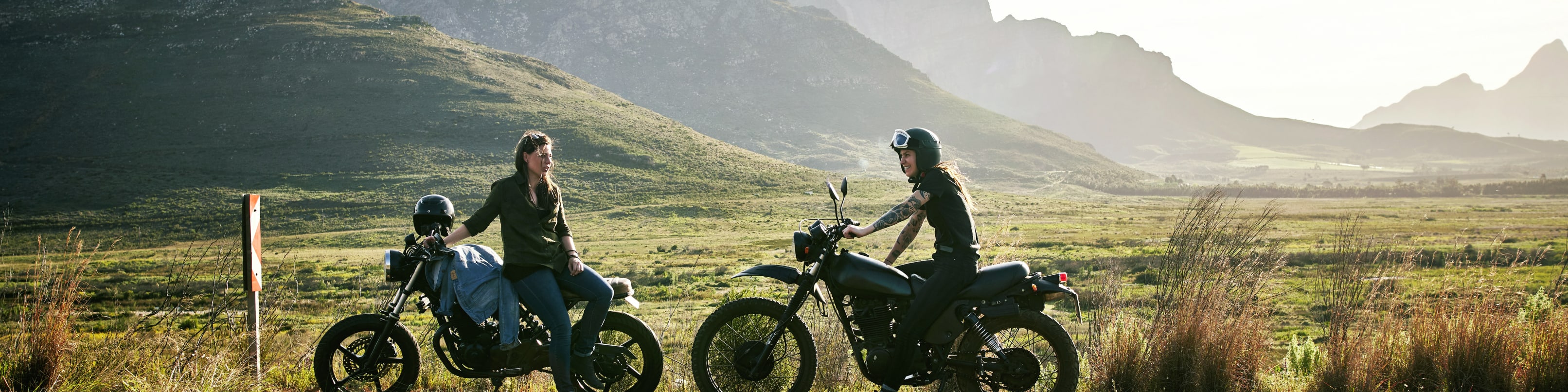 Une moto franchit un col dans un paysage de montagne alpine