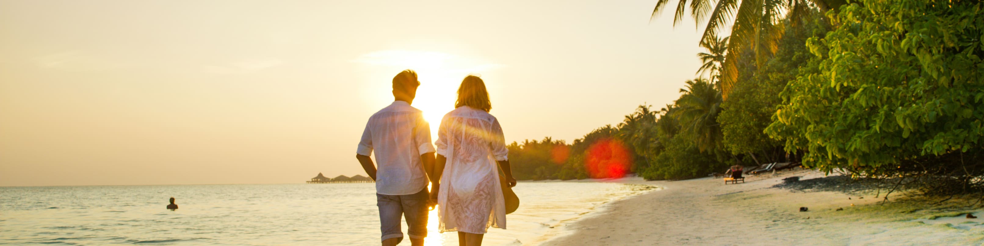 Un couple se promène sur la plage d’une station balnéaire.