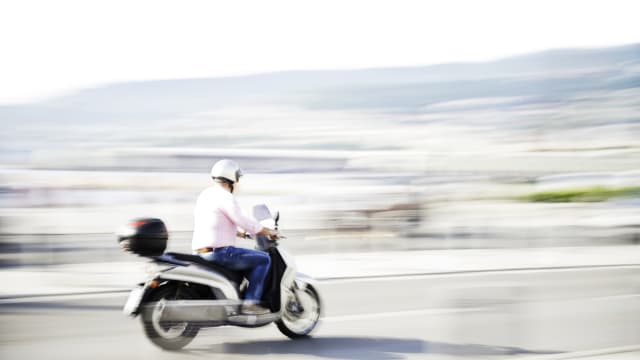 A scooter travelling over a country road at a fast pace.