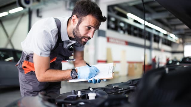 Un uomo controlla il cofano di un’auto 