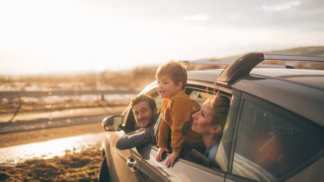 Familie sitzt in Auto und beobachtet Sonnenuntergang