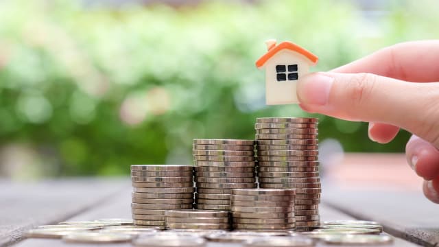 A small house that is placed on a stack of coins.