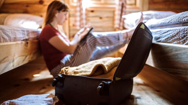 Junge Frau hat Koffer gepackt und bucht einen Flug.