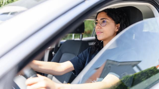 Une jeune femme au volant d’une voiture.