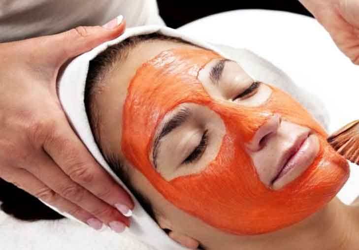 Benefícios da cenoura para a pele. A imagem mostra uma mulher fazendo uma limpeza facial usando a cenoura.
