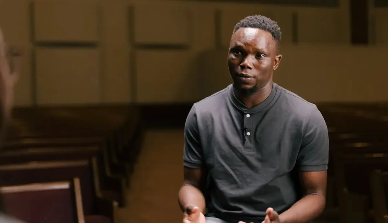 A still of Eric being interviewed in a church