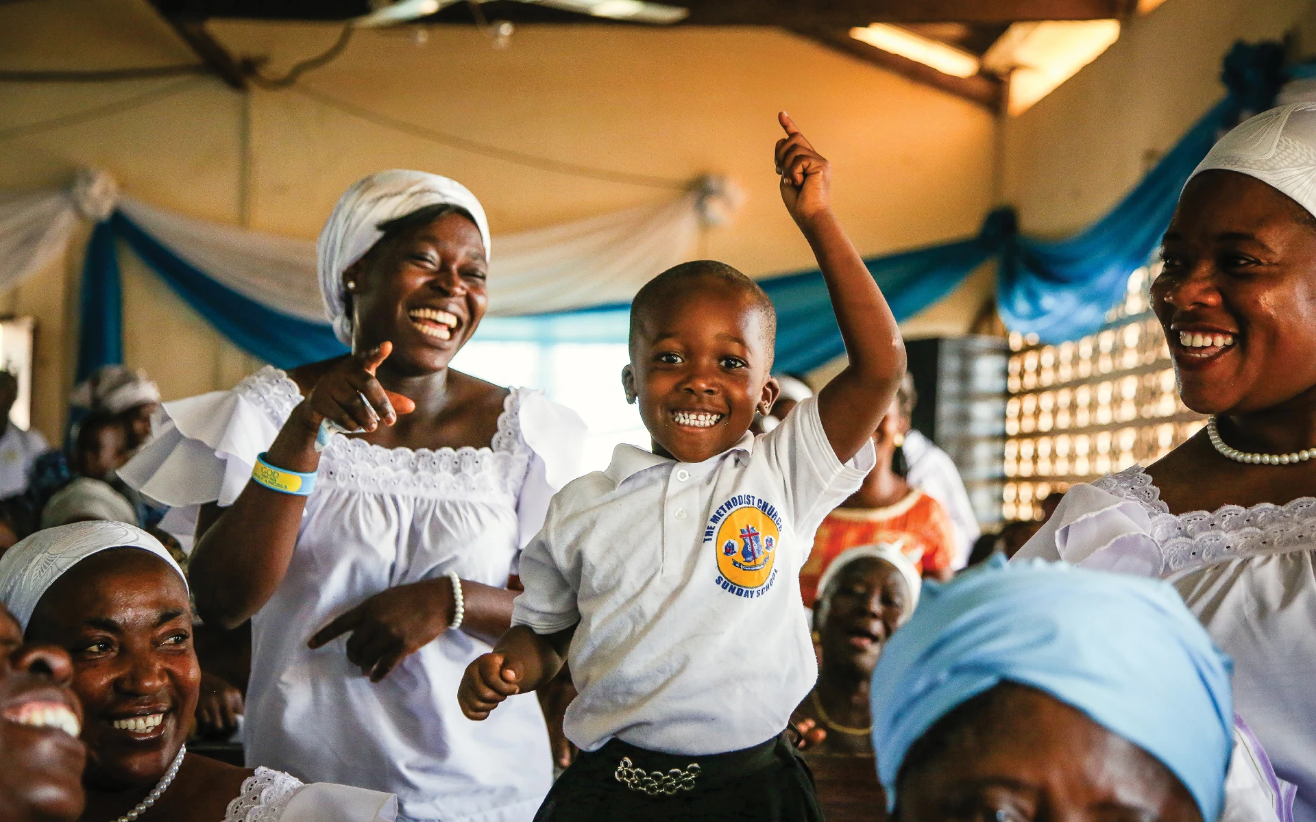 A mom and her little boy sing and laugh surrounded by other mothers.