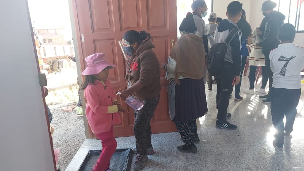 A staff member with a face shield and a mask santize children and parents as they enter the the church.