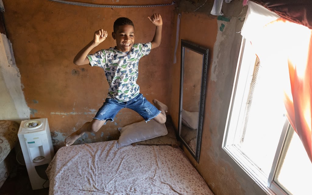 Boy jumping on the bed laughing.