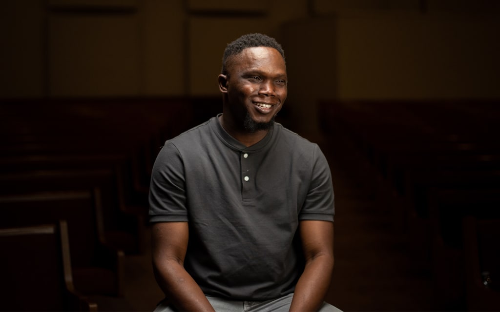 A man in a grey shirt smiles