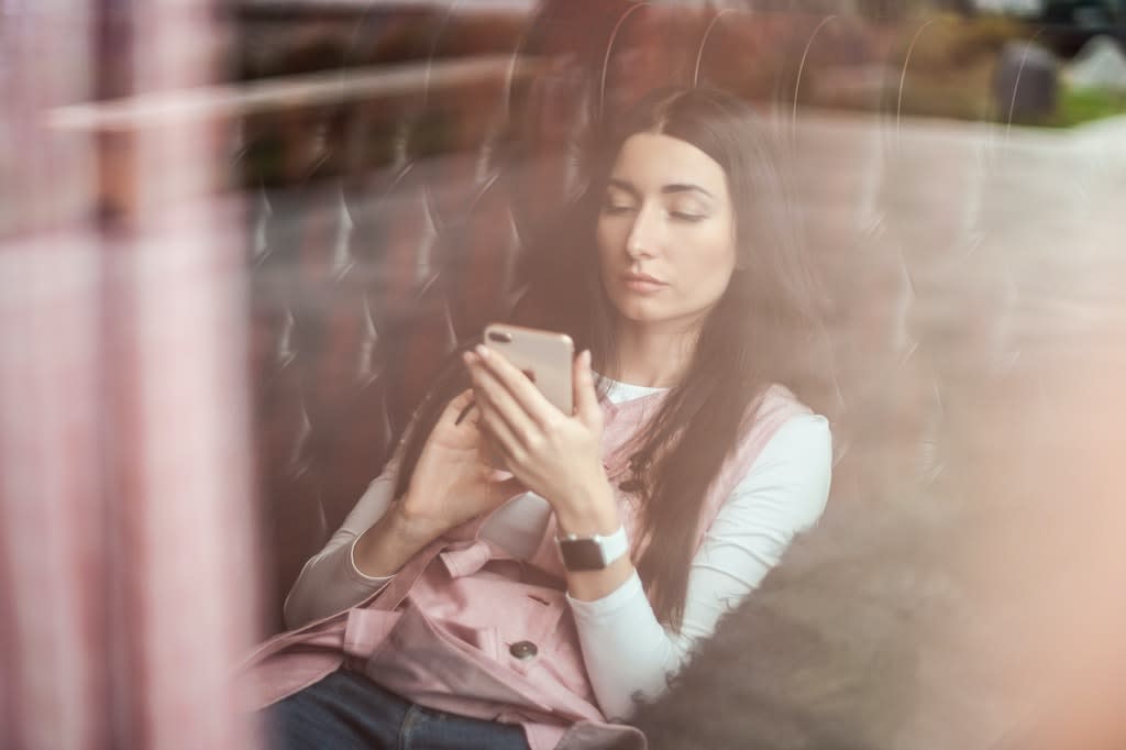 A woman leaning back in a chair and scrolling on her smart phone.