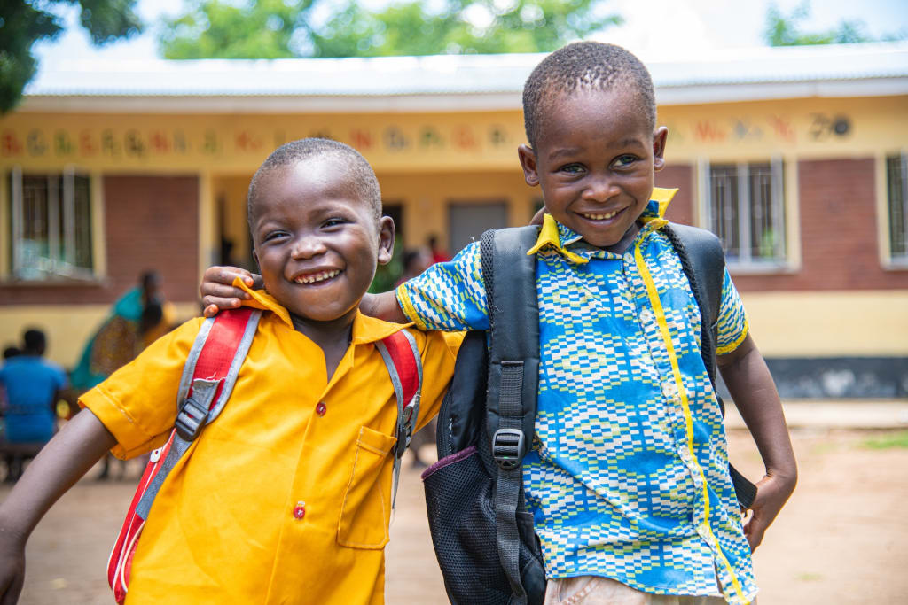 Two young boys walking outside together.