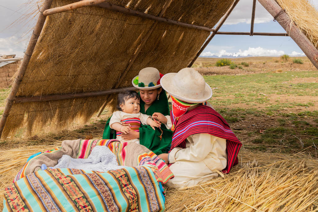 Boy and girl are dressed up like Mary and Jospeh with baby Jesus. They are on hay under a hut. Jesus is ushering in an upside-down kingdom.