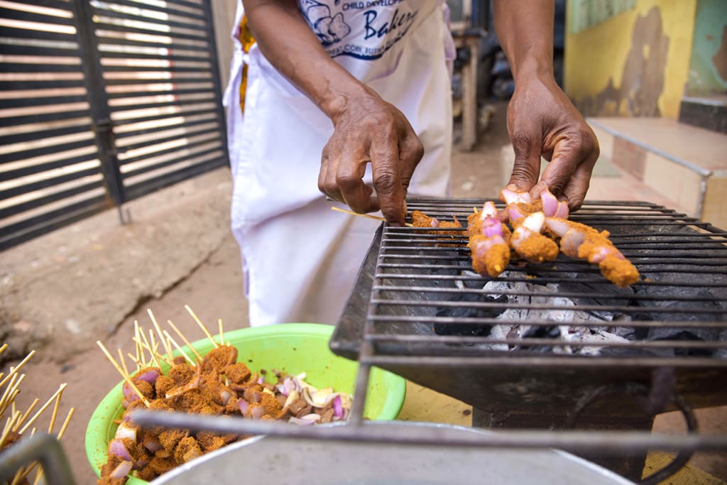Hands making kebabs on a grill.