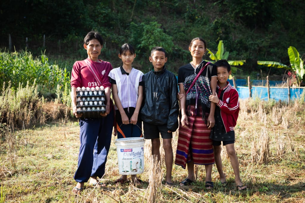 A family of five stand in a field.