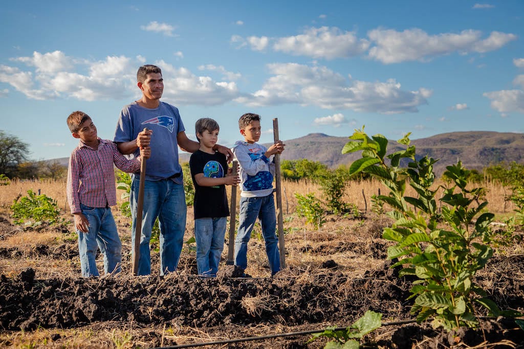 Donald and his three kids stand in a field smiling off into the distance