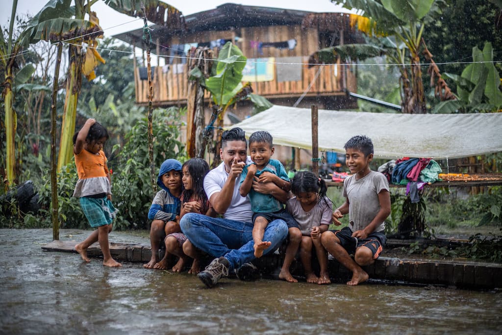 Nico sits in the rain with some Compassion kids as he captures their stories.