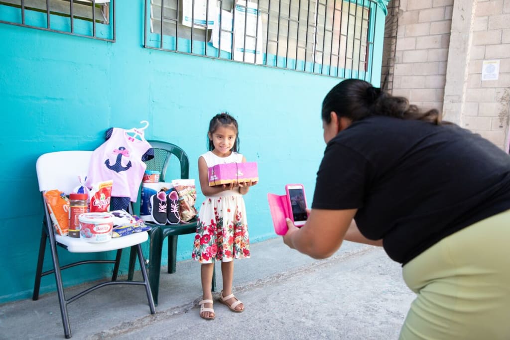 A girl in a colourful dress stands for a picture with birthday gifts