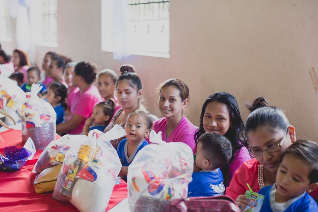 Women in pink sit with their babies in their lap.