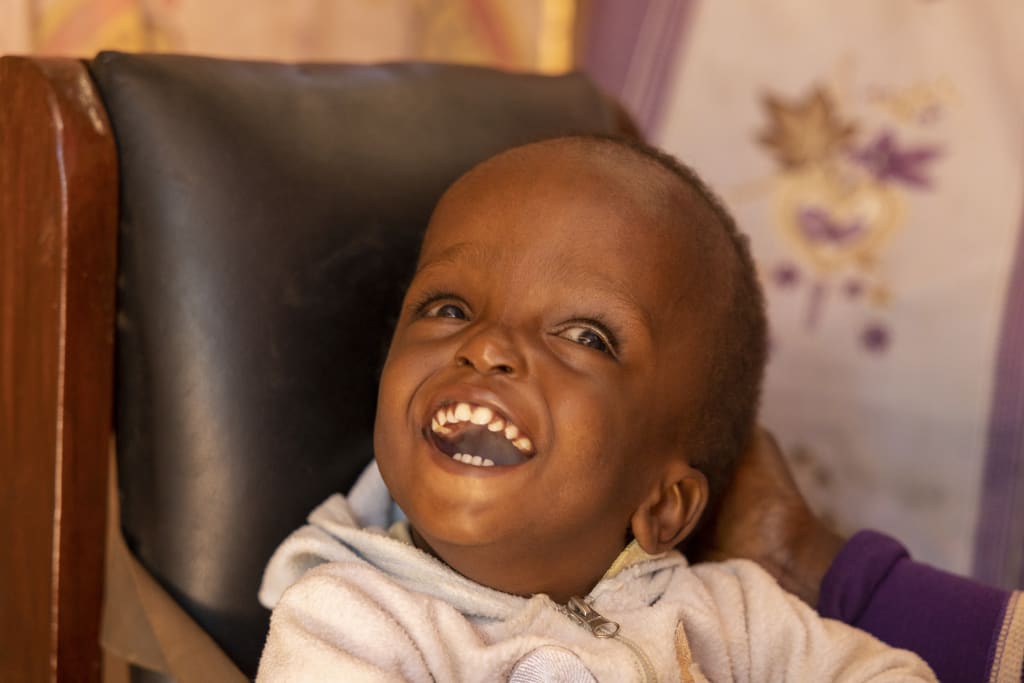 A little boy in a white hoodie laughs.