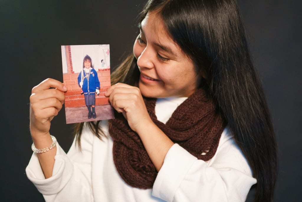 Liz, a young Peruvian woman, holds up a picture of her a a sponsored child