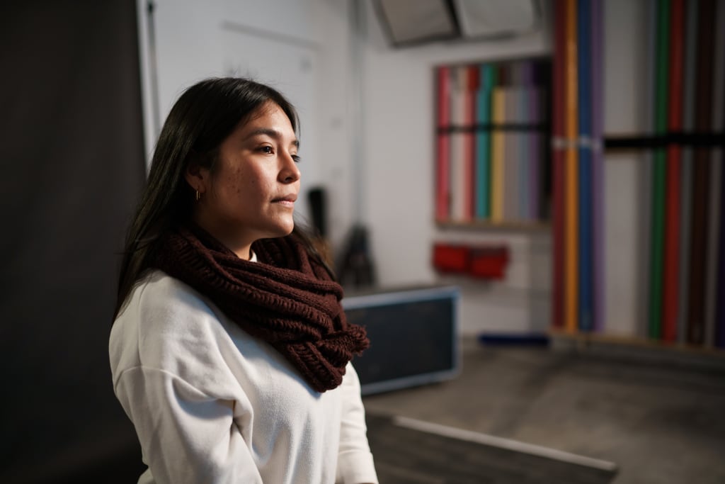 Liz, a young Peruvian woman, sits and stares into the distance